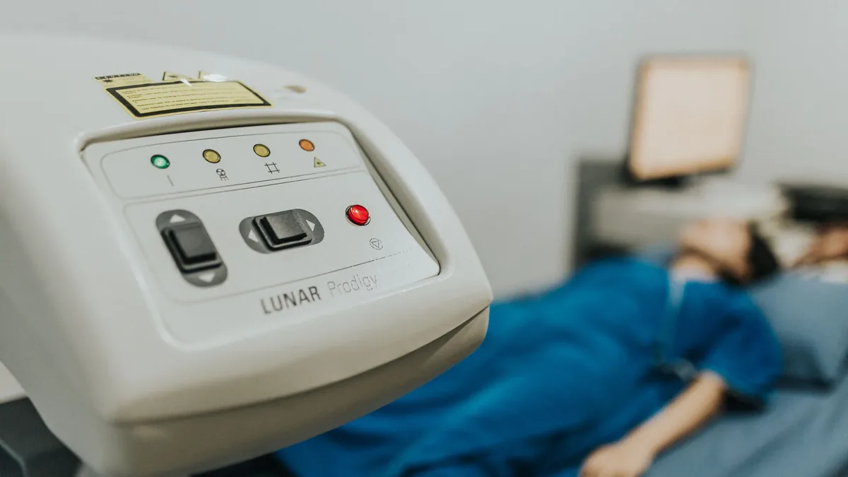 A person lying on a medical bed with a device in the foreground.