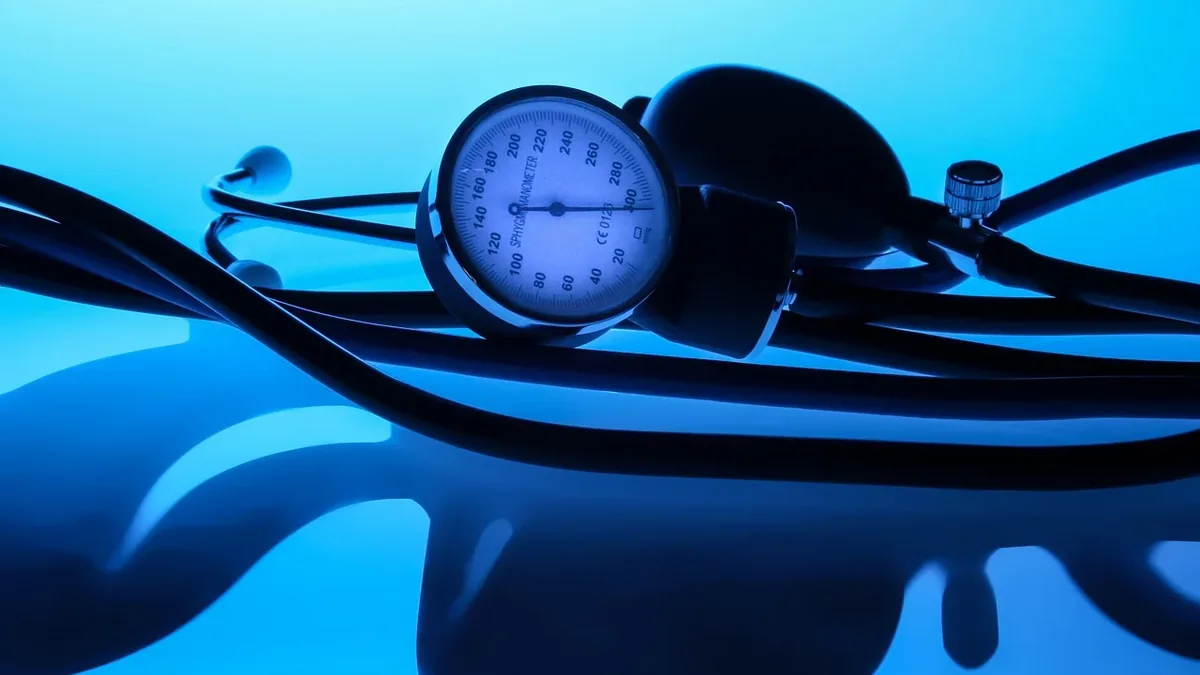 A stethoscope and a blood pressure cuff, with the stethoscope lying on top of the cuff.